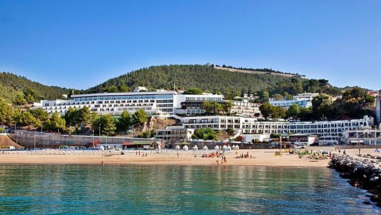 A beach with a large building and a hill

Description automatically generated with medium confidence